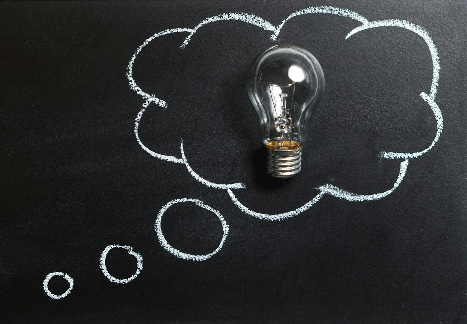 clear light bulb placed on chalkboard